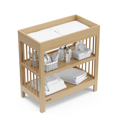 Graco Teddi Changing Table with Water-Resistant Changing Pad (Driftwood) - GREENGUARD Gold Certified, 2 Open Shelves, Includes Bonus Water-Resistant Changing Pad with Safety Strap 🍁 All In One Marketplace Canada